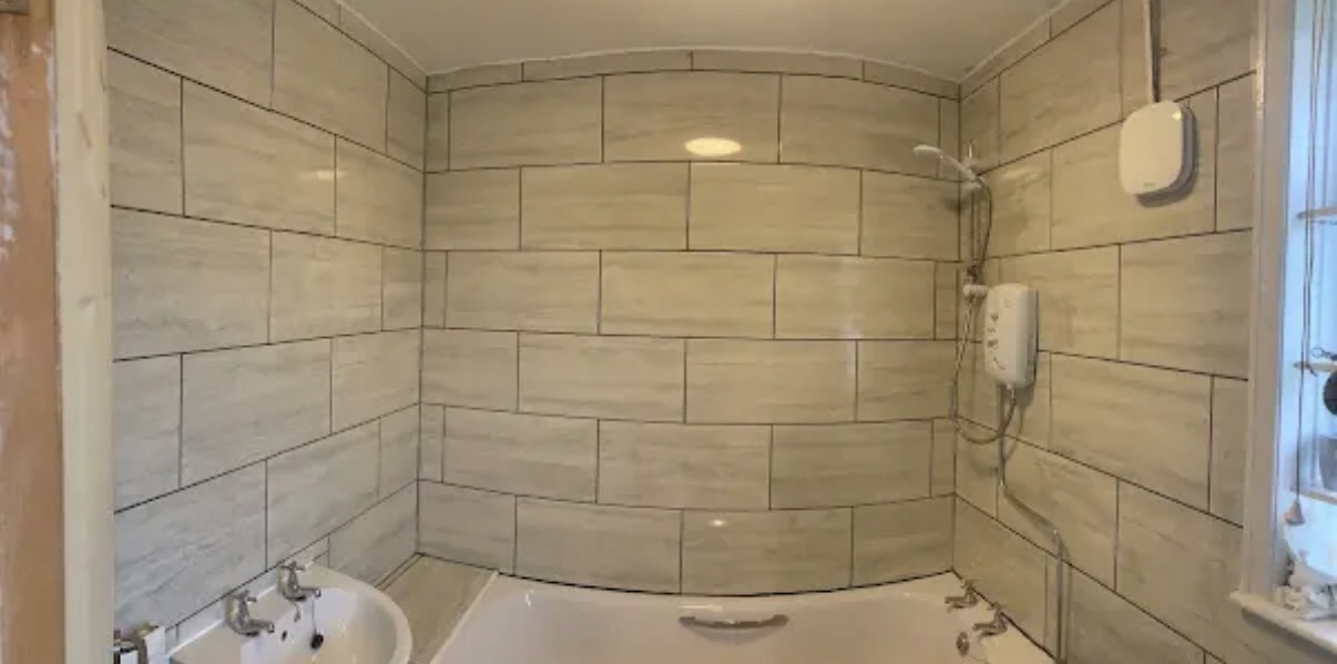 Completed tiled bathroom walls around a bath and shower