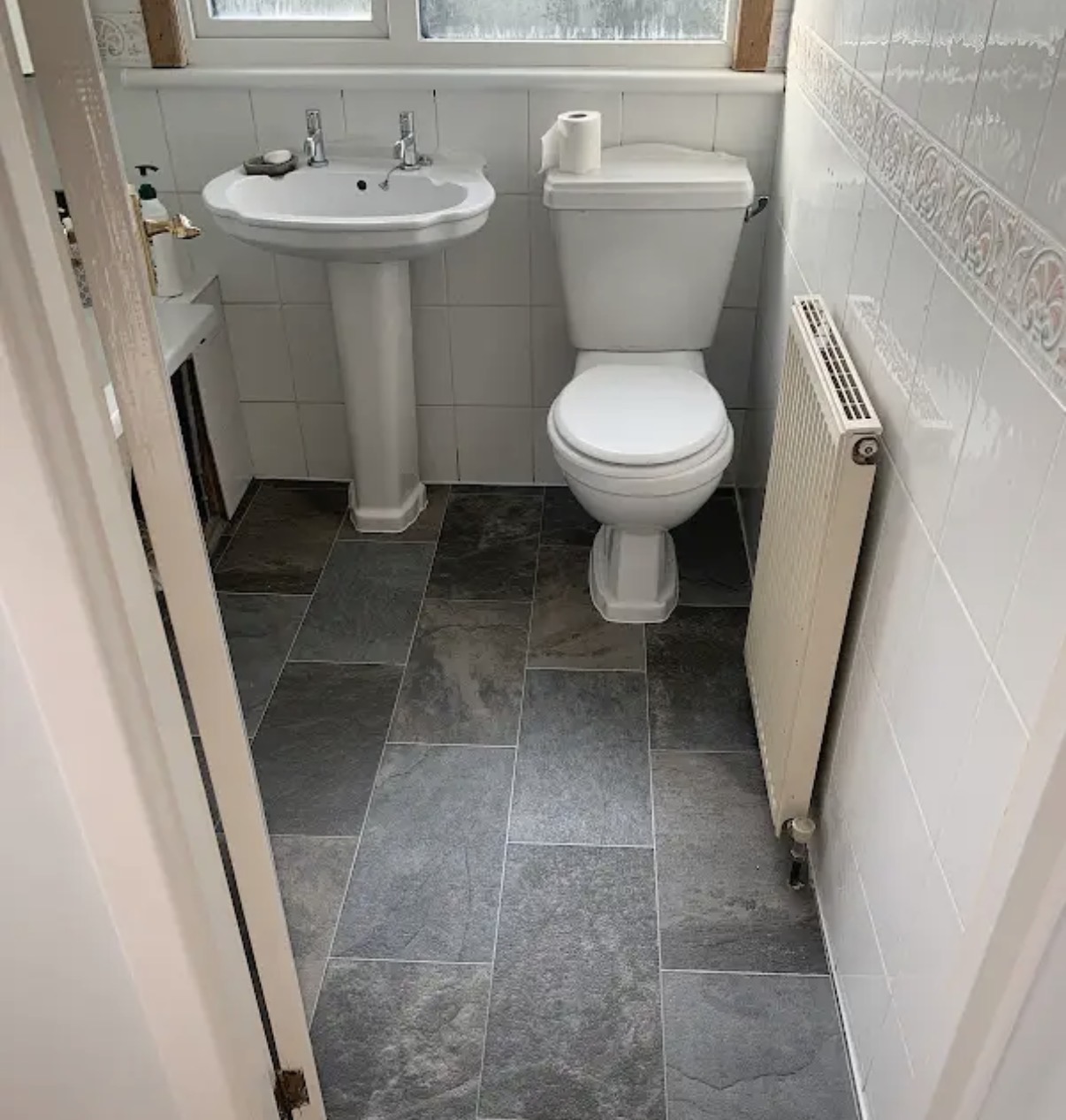 Finished dark bathroom floor tiling around sanitaryware